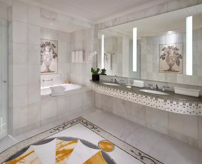 Modern bathroom with a large wall-mounted lighted mirror above a double sink.